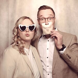 Zwei Personen vor der Fotobox mit lustigen Brillen und Schildern